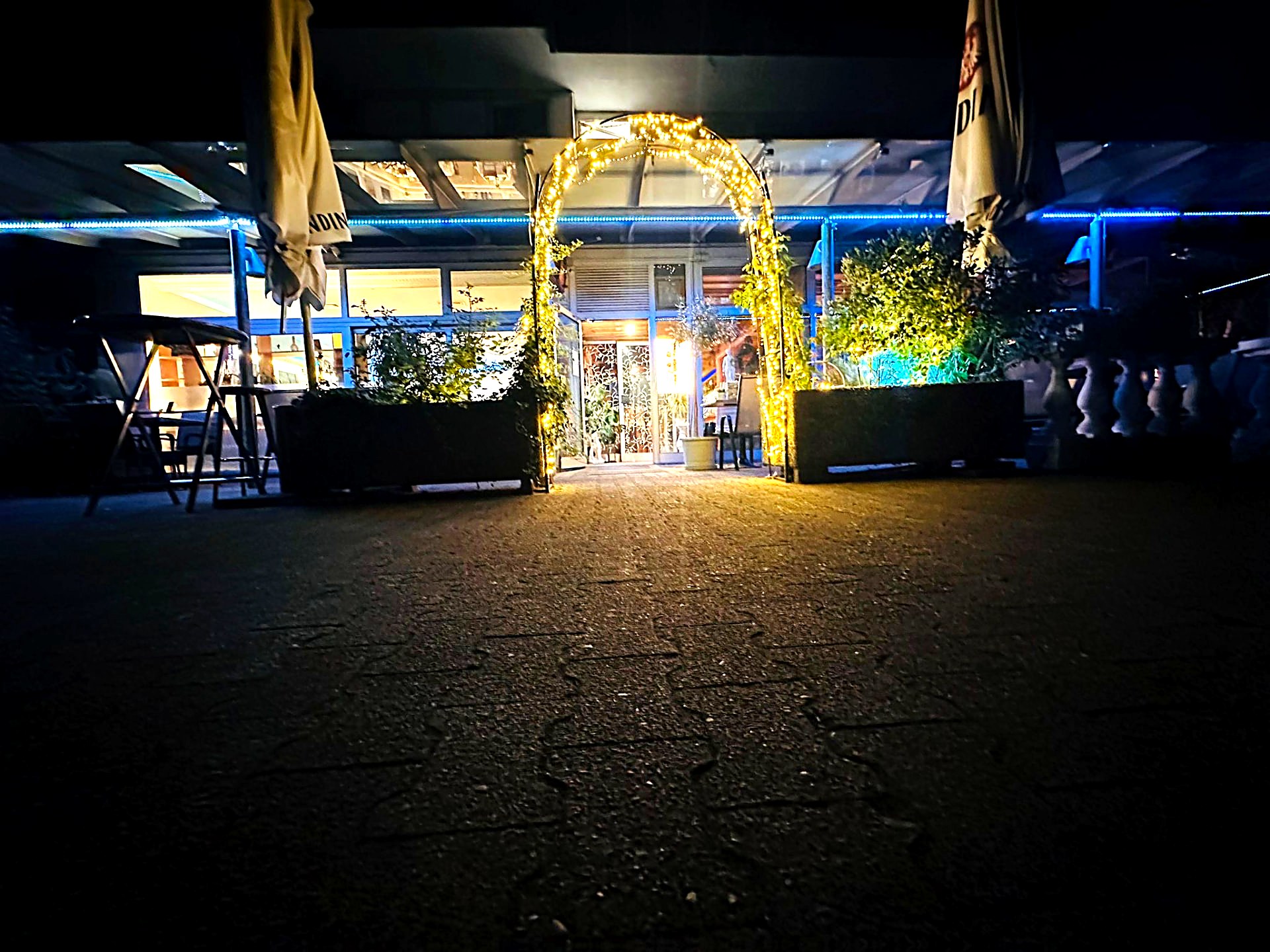 Beleuchteter Eingang von Restaurant Olympos am Abend in Rodgau